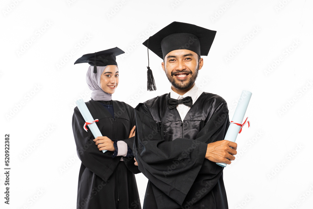 Male graduate student wearing a togas holding a certificate standing in front of his friend on an isolated background Male graduate student wearing a togas holding a certificate standing in front of his friend on an isolated background