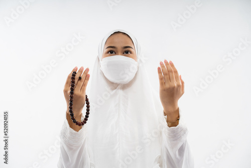 Woman in hijab wearing ihram praying al fatihah with prayer beads on isolated background photo