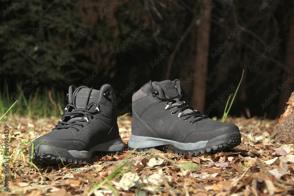 Black boots in the dark forest between trees ready for hiking in the mountains to explore at night Black boots in the dark forest between trees ready for hiking in the mountains to explore at night