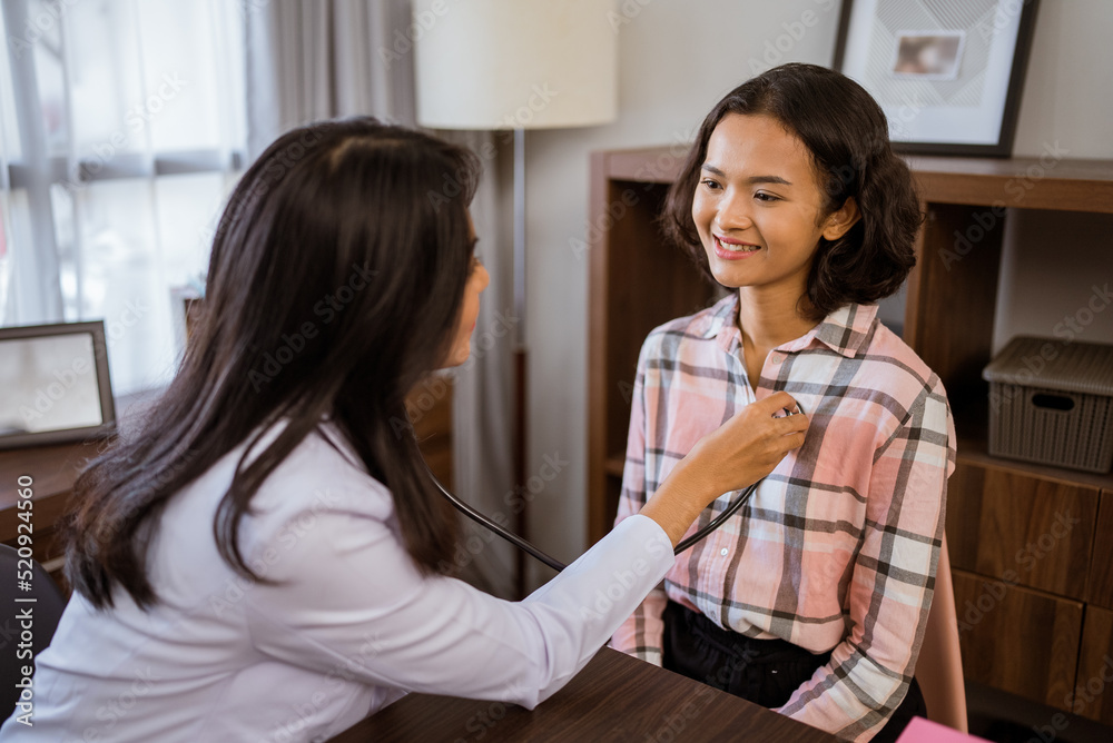 female doctor examining female patient's chest using a stethoscope in clinic room female doctor examining female patient's chest using a stethoscope in clinic room