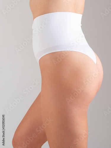 Attractive young woman standing in underwear, belly and hips. vertical photo