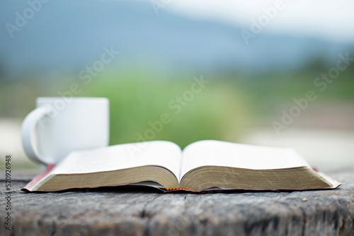 Vászonkép Open the bible with a cup of coffee for morning devotion on a wooden table with nature background