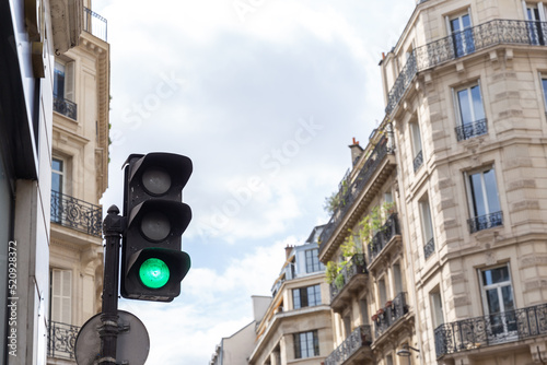 Traffic light with red light with facades of Parisian buildings on a bright day