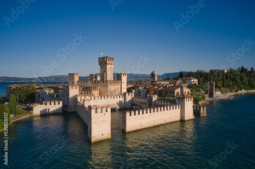 Aerial view of Scaligero Castle at sunrise. Historic Water Castle on Lake Garda. Sirmione aerial view on Lake Garda, Italy.