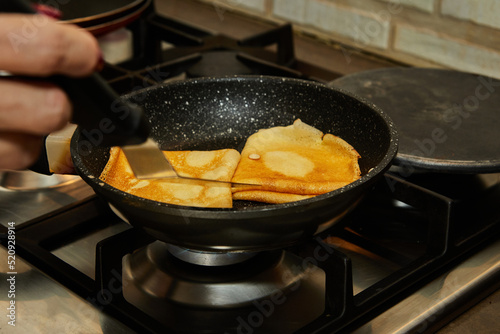 Chef pan-frying Crepe Suzette pancakes with cognac and citrus sauce