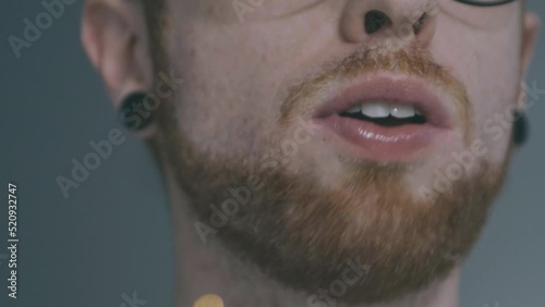 Slow motion detail of a boy eating an orange mango popsicle, the boy has red hair and dilators photo