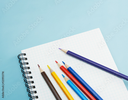 水色の机の上のノートにあるカラフルな色鉛筆