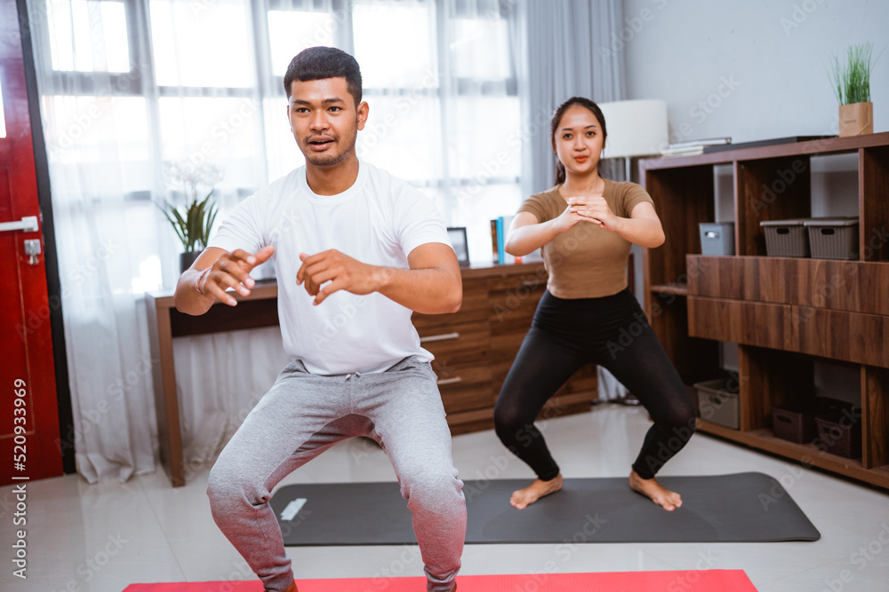 portrait of young asian couple workout together at home stretching their body portrait of young asian couple workout together at home stretching their body
