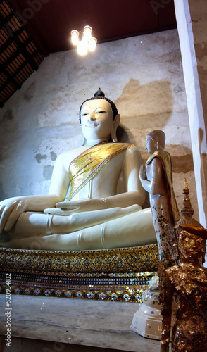 Low angle view of big buddha statue inside an old Thai temple.