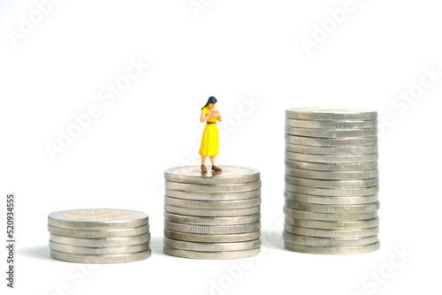 Miniature people toy figure photography. A girl student standing above money coin stack, isolated on white background