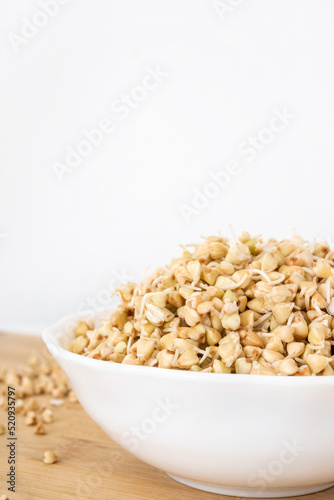Bowl of raw organic germinated buckwheat on white background with copy space. Protein grain for detox salad.