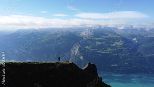 Rotating aerial view of a hiker standing with a view of Lake Brienz, near to Brienzer Rothorn on a clear blue day in Switzerland photo