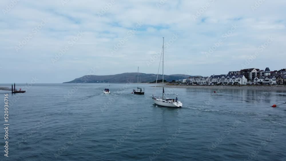 Aerial orbiting view following sailing boats travelling scenic Welsh village river estuary Aerial orbiting view following sailing boats travelling scenic Welsh village river estuary