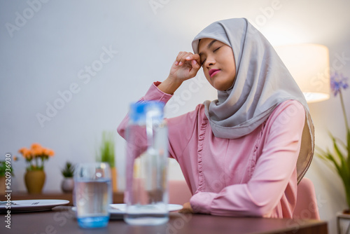 tired muslim woman wake up early to have a morning breakfast on fasting month. sahur concept in ramadan photo