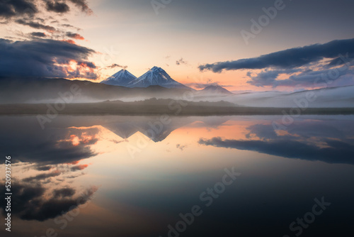 Volcanoes and their reflections in the lake at sunrise in Kamchatka, Russia.