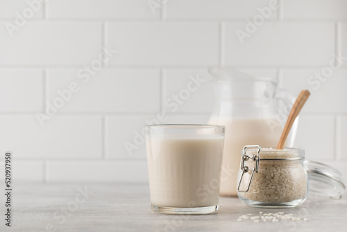 A glass of rice milk, a jug of alternative milk and a jar of rice. Copy space photo
