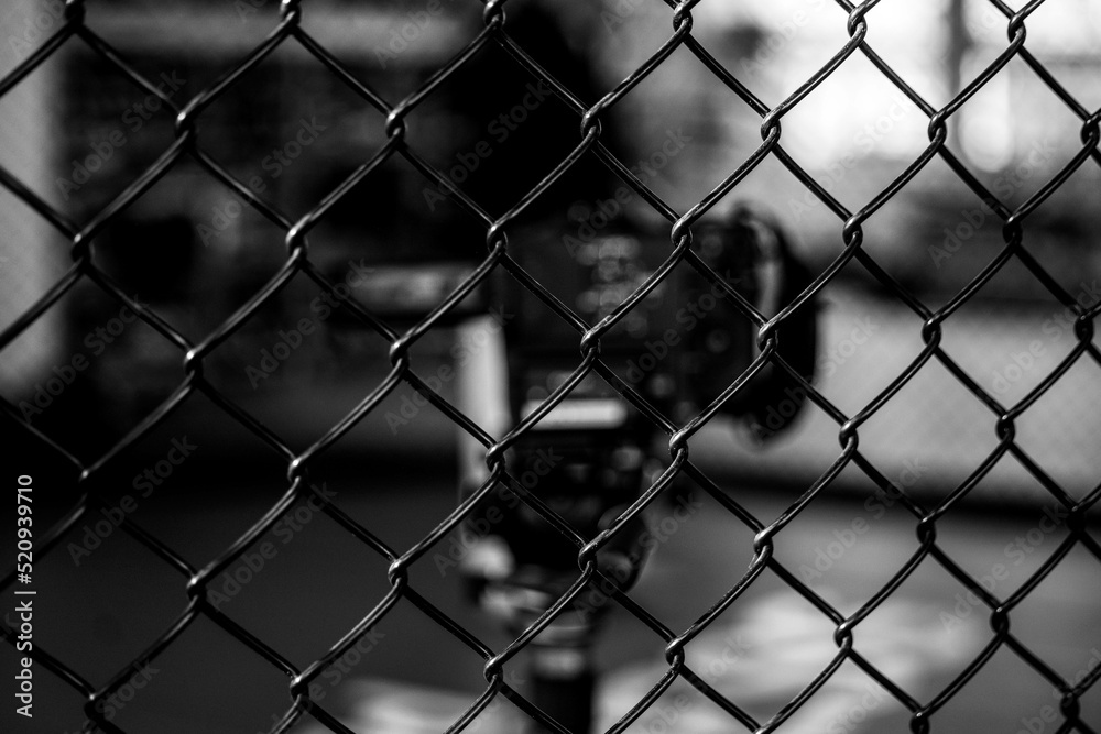 A video camera behind a fence wire A video camera behind a fence wire