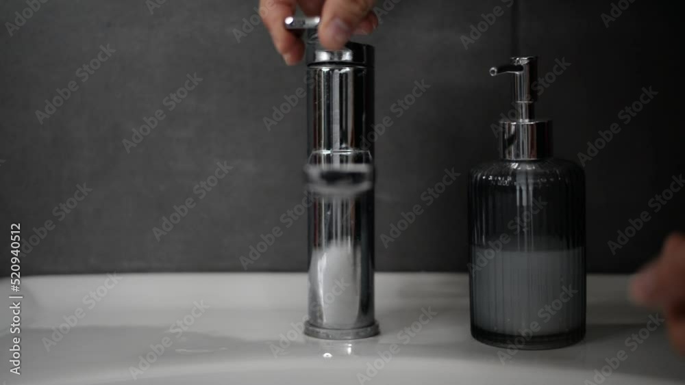 Washing hands with soap at a beautiful interior washbasin of a bathroom with gray walls. Washing hands with soap at a beautiful interior washbasin of a bathroom with gray walls.