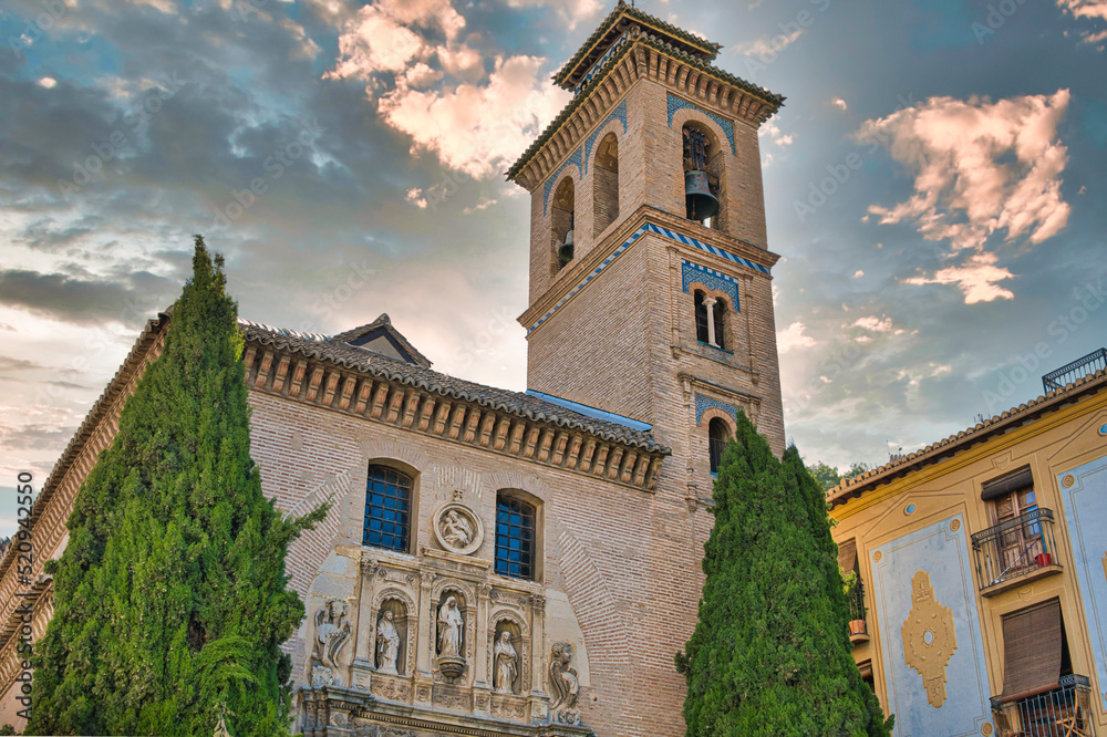 Iglesia de san Gil y santa Ana de estilo mudéjar y siglo XVI con el sol detrás al amanecer en Granada, España