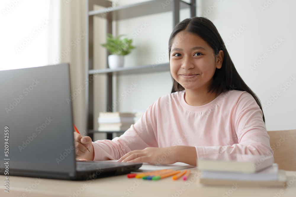 Asian school girl studying online class on laptop. Happy kid enjoy learning from home using laptop. Asian school girl studying online class on laptop. Happy kid enjoy learning from home using laptop.