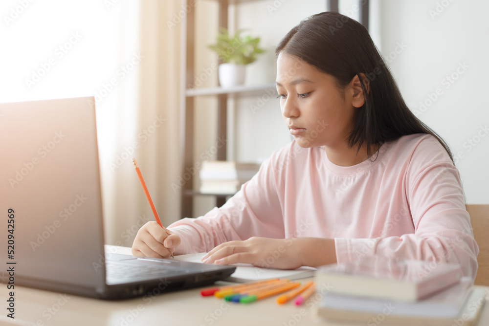 Asian school girl studying online class on laptop. Happy kid enjoy learning from home using laptop. Asian school girl studying online class on laptop. Happy kid enjoy learning from home using laptop.