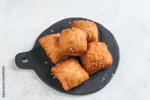 Bolang baling, Odading, fried bread in cubes or blocks, with a light brown crunchy outer skin and sprinkled with sesame seeds, the inside is empty and fluffy, so it looks like a small pillow.
 photo