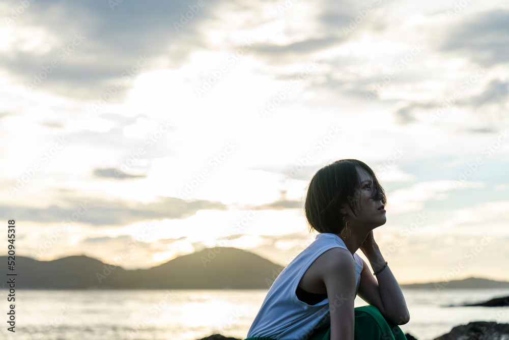 夕暮れの海にいる女性