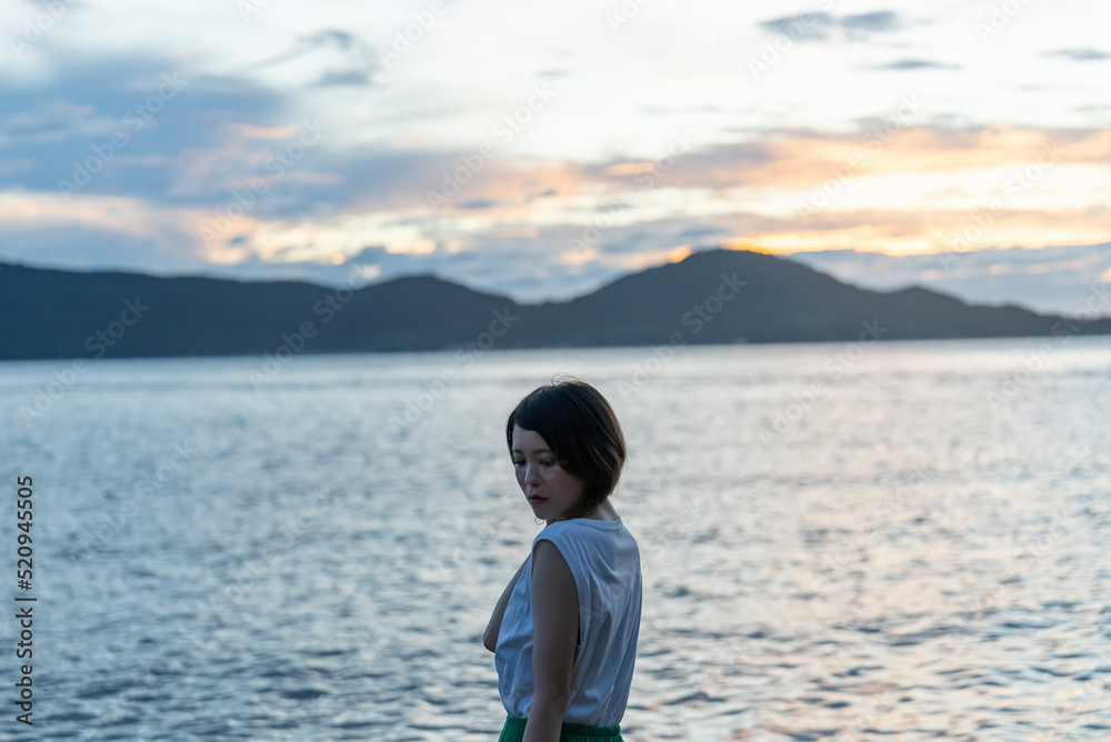 夕暮れの海にいる女性