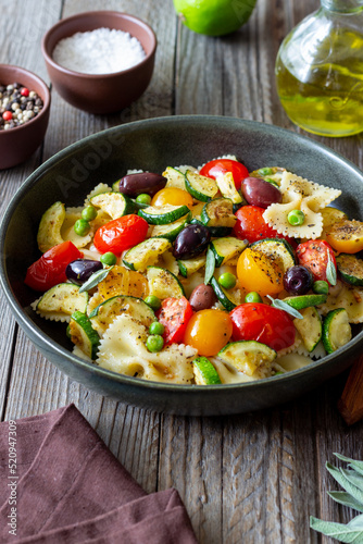 Pasta farfalle with tomatoes, zucchini, peas, Kalamata olives and sage. Healthy eating. Vegetarian food.