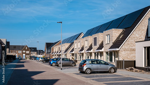 Newly build houses with solar panels attached on the roof against a sunny sky Close up of a new building with black solar panels. Zonnepanelen, Zonne energie, Translation: Solar panel, , Sun Energy.  photo