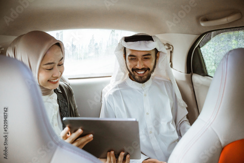 muslim business partner discussing and meeting using tablet pc presenting project while sitting on a car photo