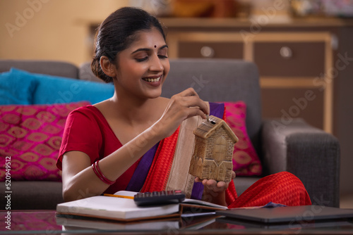 Portrait of cheerful young woman inserting coin inside money box photo