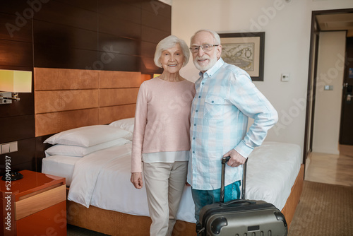 Senior happy couple in a hotel room looking cheerful and excited