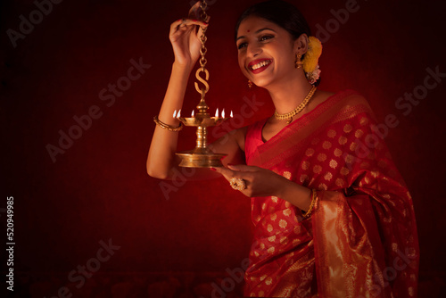 Woman in traditional outfit lighting oil lamp on the occasion of Diwali photo