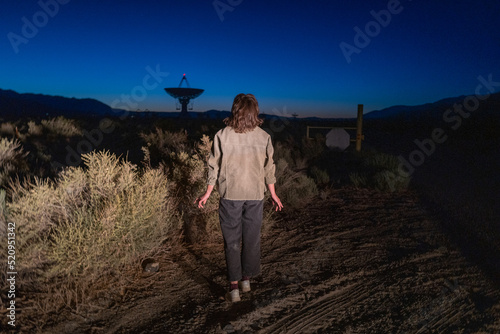 a person appears to be abucted by aliens in a sci-fi looking scene near radio astronomy telescope