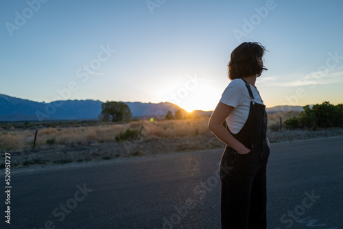 Young woman gazes into distance in desert landscape as last light of sunset descends photo