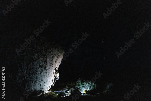 Night shot of solitary rock climber in headlamp on large boulder photo