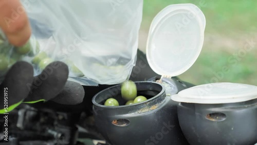 Loading a paintball gun with green ammo balls in closeup.