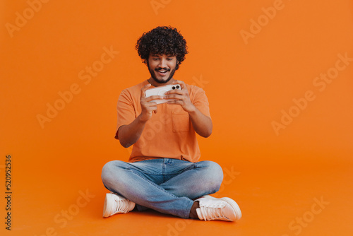 Young indian handsome curly man playing mobile game © Drobot Dean