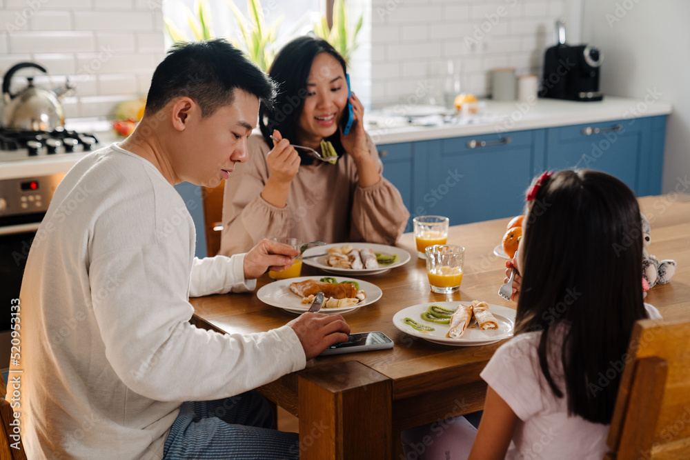 Happy asian family with little daughter having breakfast at home Happy asian family with little daughter having breakfast at home