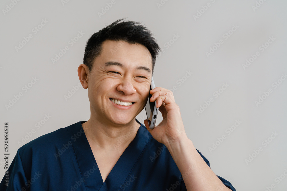 Asian health worker wearing uniform laughing while talking on cellphone