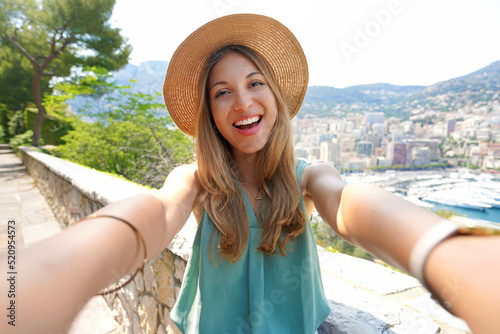 Attractive tourist girl takes selfie picture with Monte-Carlo cityscape, Monaco