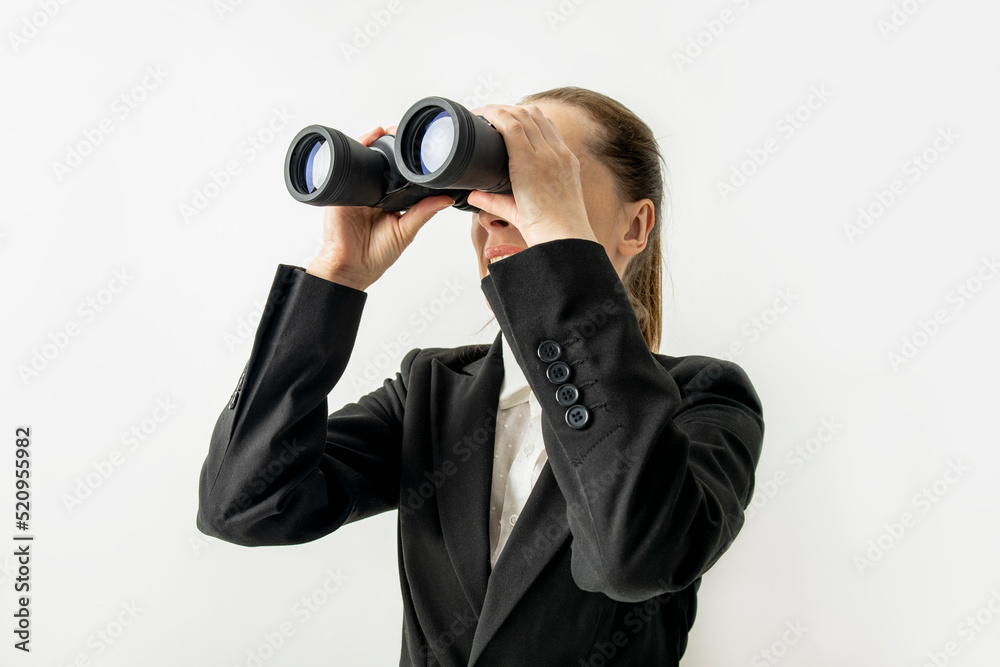Smiling business woman in jacket looking through binoculars on white background