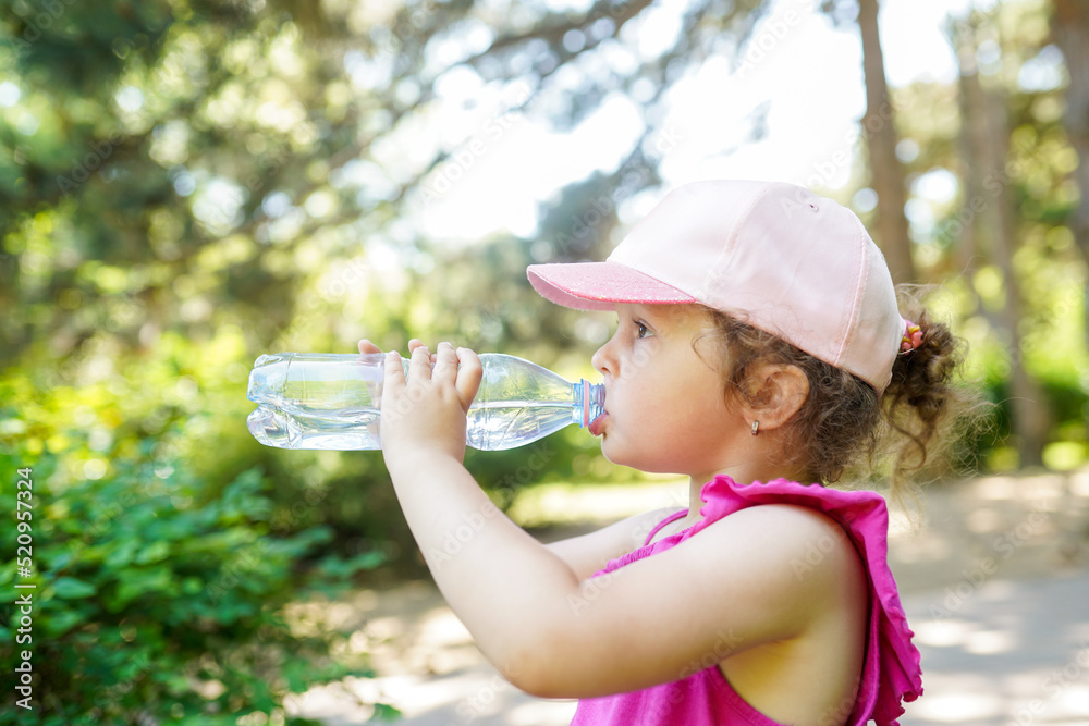 Child girl drinks mineral water from a bottle in the park Child girl drinks mineral water from a bottle in the park