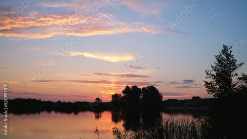 Colorful summer sunset on the river bank.Natural landscape. Reflection, blue sky and yellow sunlight © kseniaso