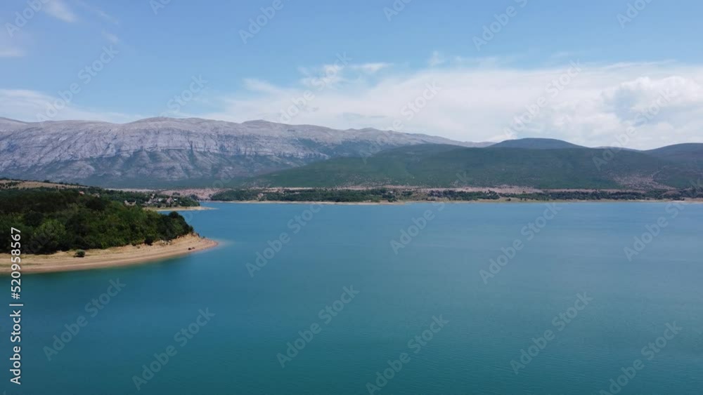 in front the deep blue croatian lake perucko with bright beach, behind the imposing dinara mountains in nice sunny weather in front the deep blue croatian lake perucko with bright beach, behind the imposing dinara mountains in nice sunny weather
