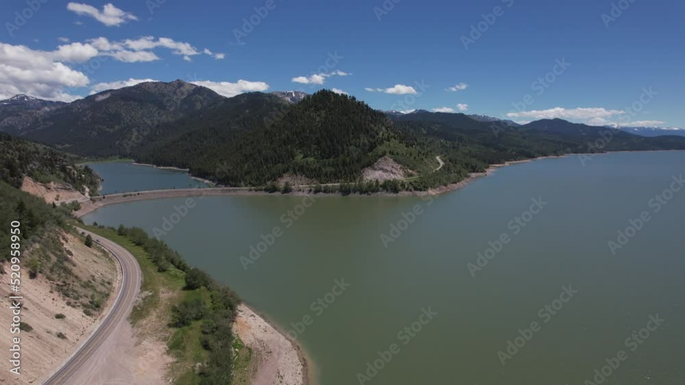 Drone flying, turns left to reveal an arm of the reservoir. A dam with a road is seen dividing the arm from the reservoir. Drone flying, turns left to reveal an arm of the reservoir. A dam with a road is seen dividing the arm from the reservoir.