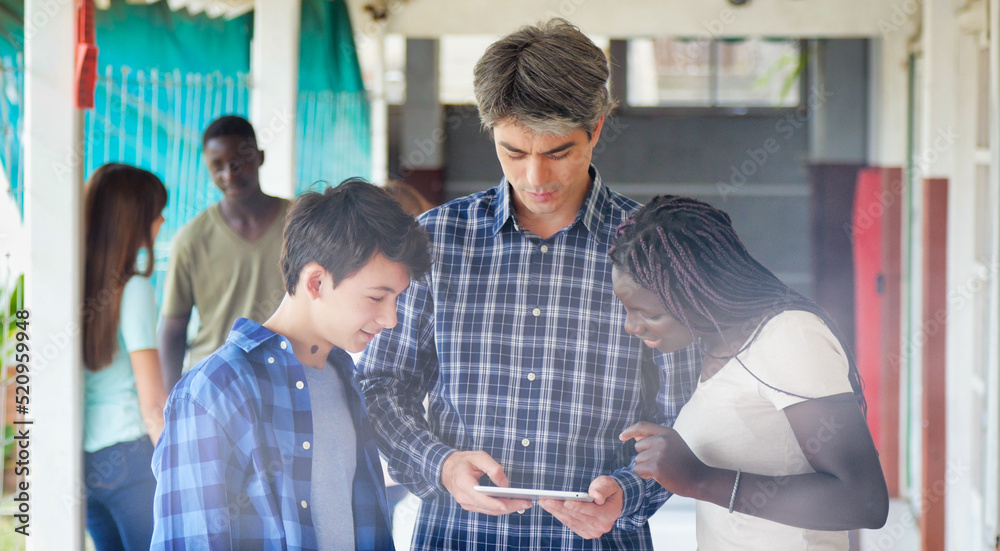 Fototapeta premium Teacher in the school hallway discussing with his teenager multi ethnic classroom