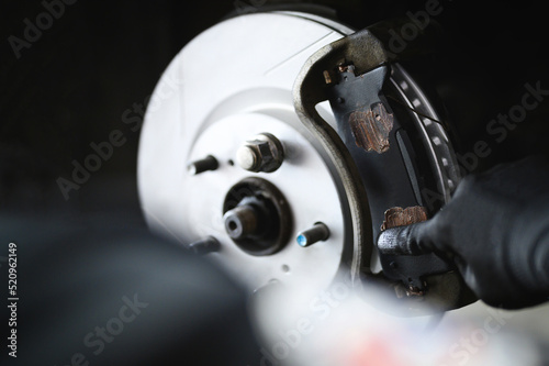 Auto mechanic installing car front brake pads.