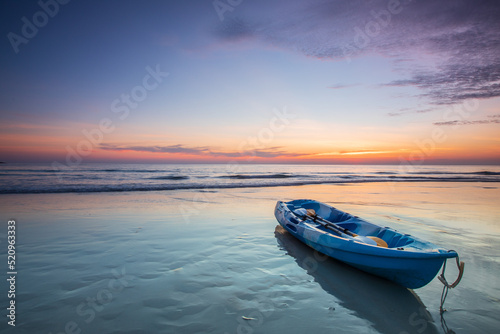 Blue canoe on the beach with sunset at Trat province, Thailand.